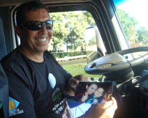 7_Adriano_leva_consigo_fotos_da_família_as_quais_ele_exibe_orgulhosamente_com_um_sorriso_de_orelha_a_orelha_-__por_Nana