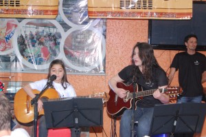 Professores de música auxiliando alunos durante as apresentações. Foto: Tamires Zortéa.