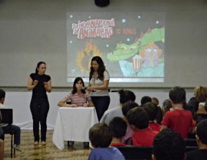 Rúbia lendo um poema em braile com tradução de uma intérprete de LIBRAS. Foto: Eduarda Wilhelm Possenti.